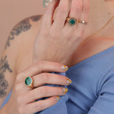 Person wearing three rings, one gold toned bronze with a green malachite inlay stone