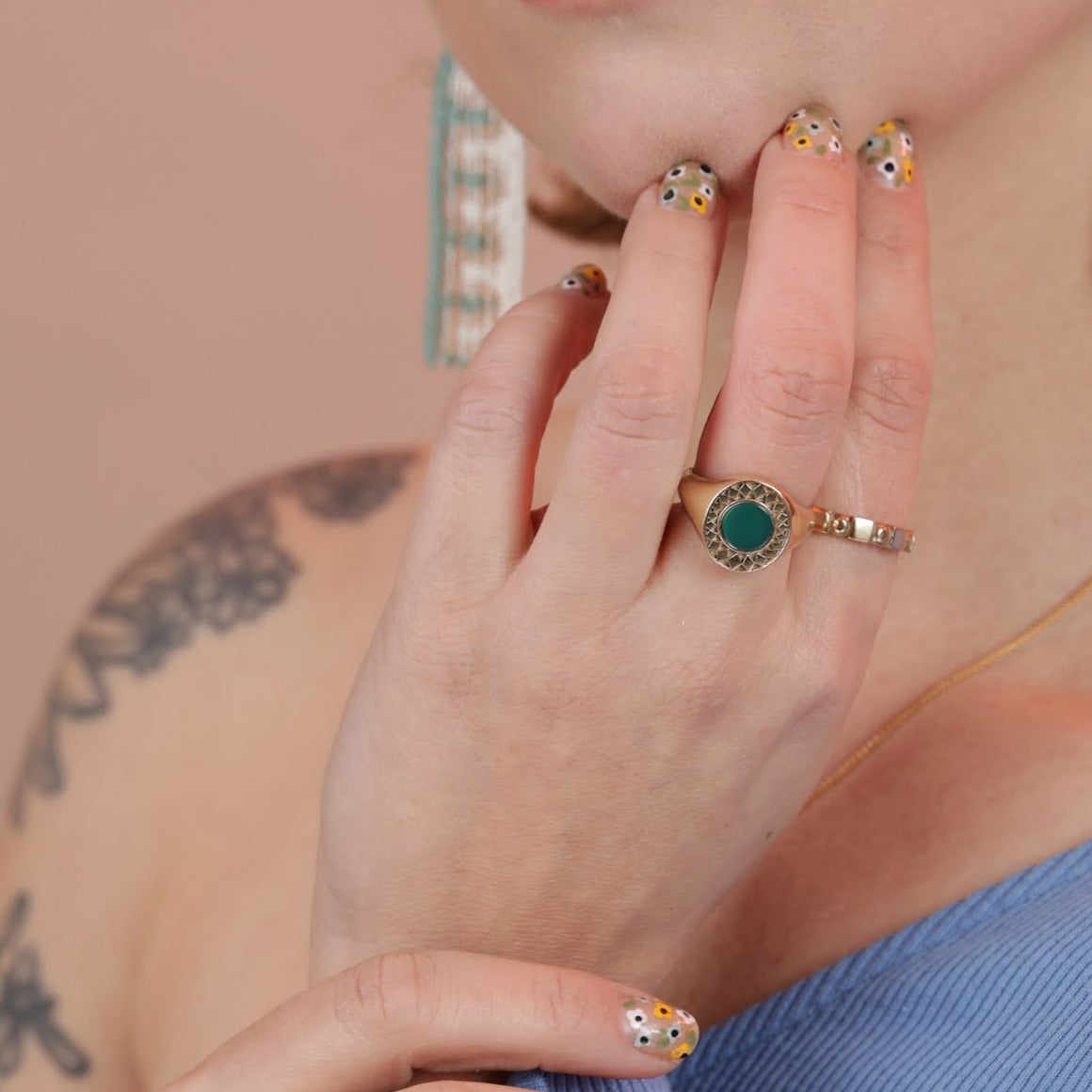 Person wearing a gold toned diamond burst ring with green chrysoprase inlay