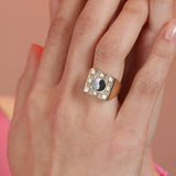 A person wearing a square checkerboard inlay ring with a visible black and white ying yang inlay design on their finger.