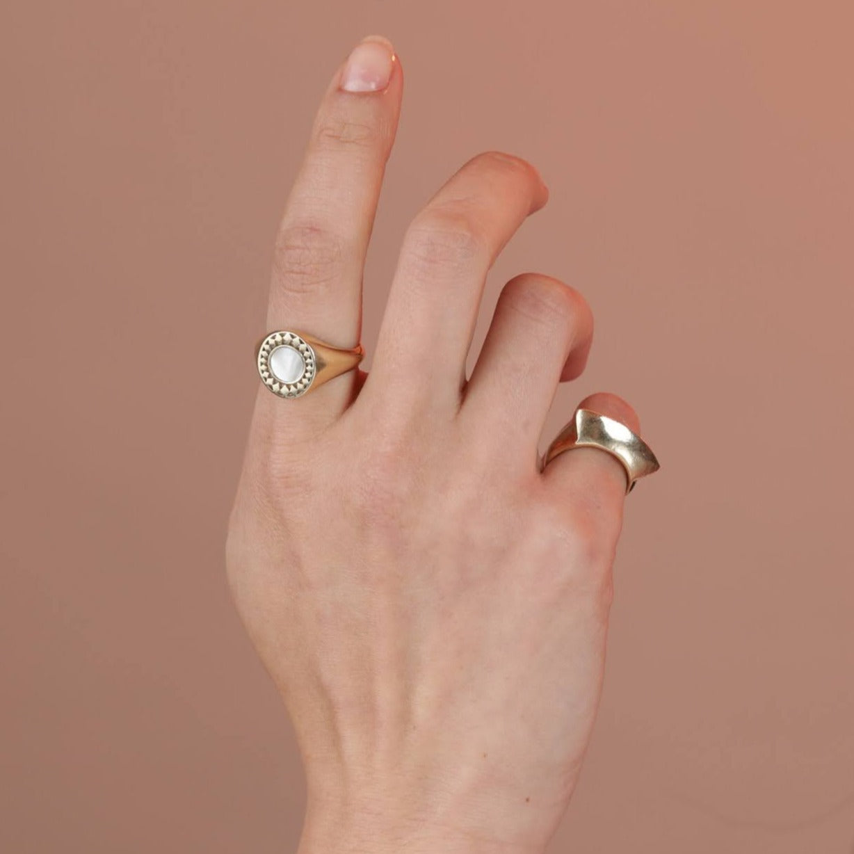Person wearing two gold tone rings, one with a star border and mother of pearl stones