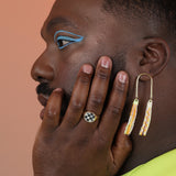 Person wearing a bronze signet with a round checkerboard stone