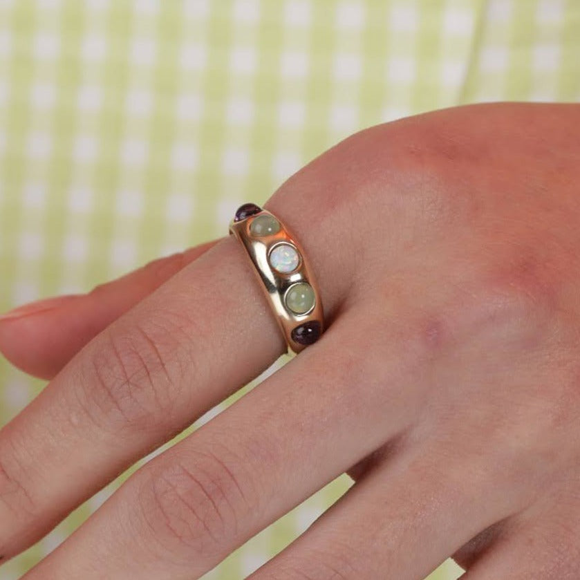 Close up of a person wearing a gold colored ring band with colorful stones