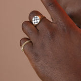Person wearing two gold colored bronze rings, one with a ridged pattern and one with a checkerboard signet face