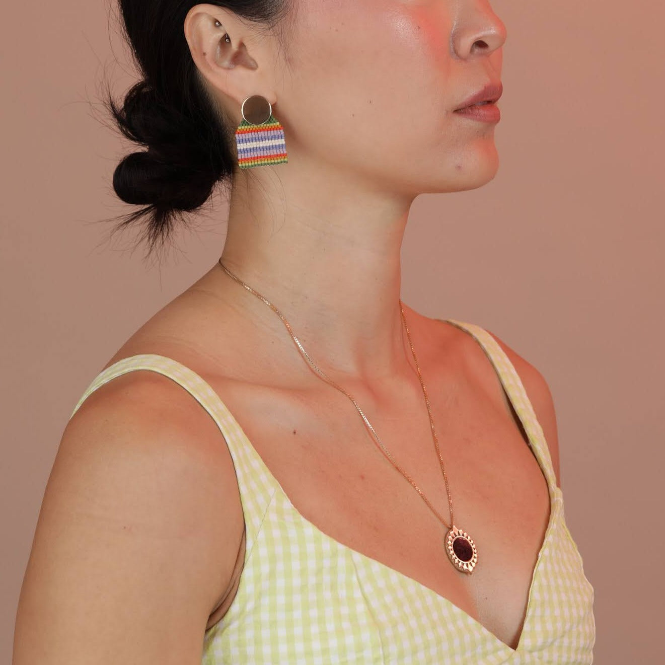 Person wearing a bronze pendant with a starburst design surrounding a black onyx inlay stone