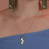 Person wearing a geometric pendant in a gold colored bronze