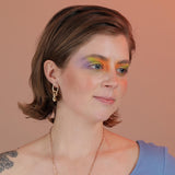 Person wearing gold colored  asymmetrical knotted earrings