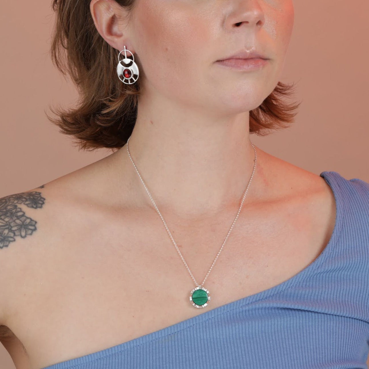 Person wearing a green malachite pendant with a silver border and chain