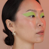 Person wearing a pair of gold colored geometric earrings