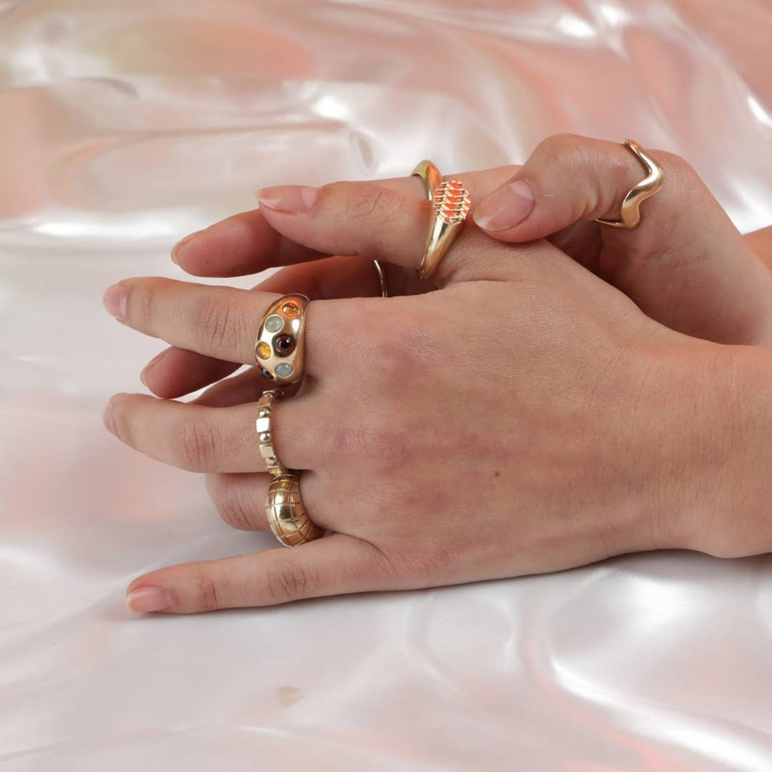 Person wearing numerous gold rings with different patterns