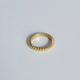 A gold-colored band ring with a geometric design, displayed on a white background.