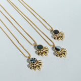 A collection of gold-colored necklaces with different inlay designs, displayed in a row on a light background.