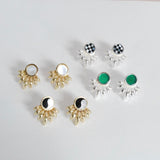 A collection of inlay earrings displayed on a surface, featuring various designs with inlayed stones in bronze or silver sunray patterns.