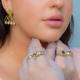 Person wearing thick gold colored rings with colorful cabochon stones