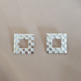 Square earrings with a checkerboard pattern in sterling silver with a cream background
