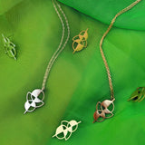 Earrings and necklaces with the same geometric, abstract shape in bronze and silver on a green background
