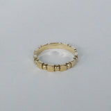Ring with alternating cube and sphere patterns in a gold bronze color on a grey background