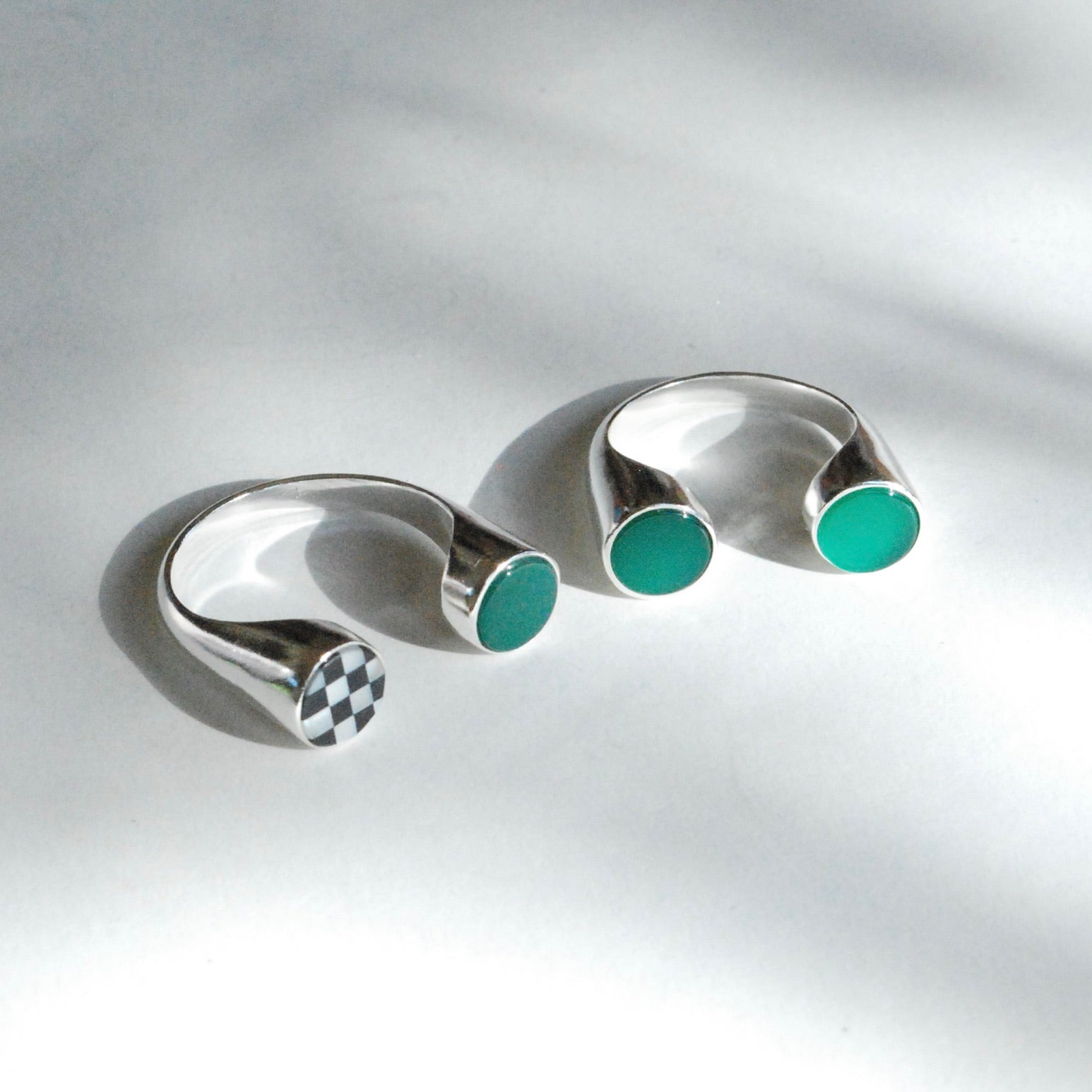 A silver ring with multiple stones inlaid in its split shank design, displayed against a grey background.