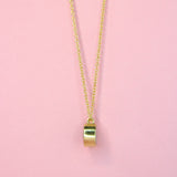 A side view of a gold toned bronze reversible charm necklace with a dainty chain 