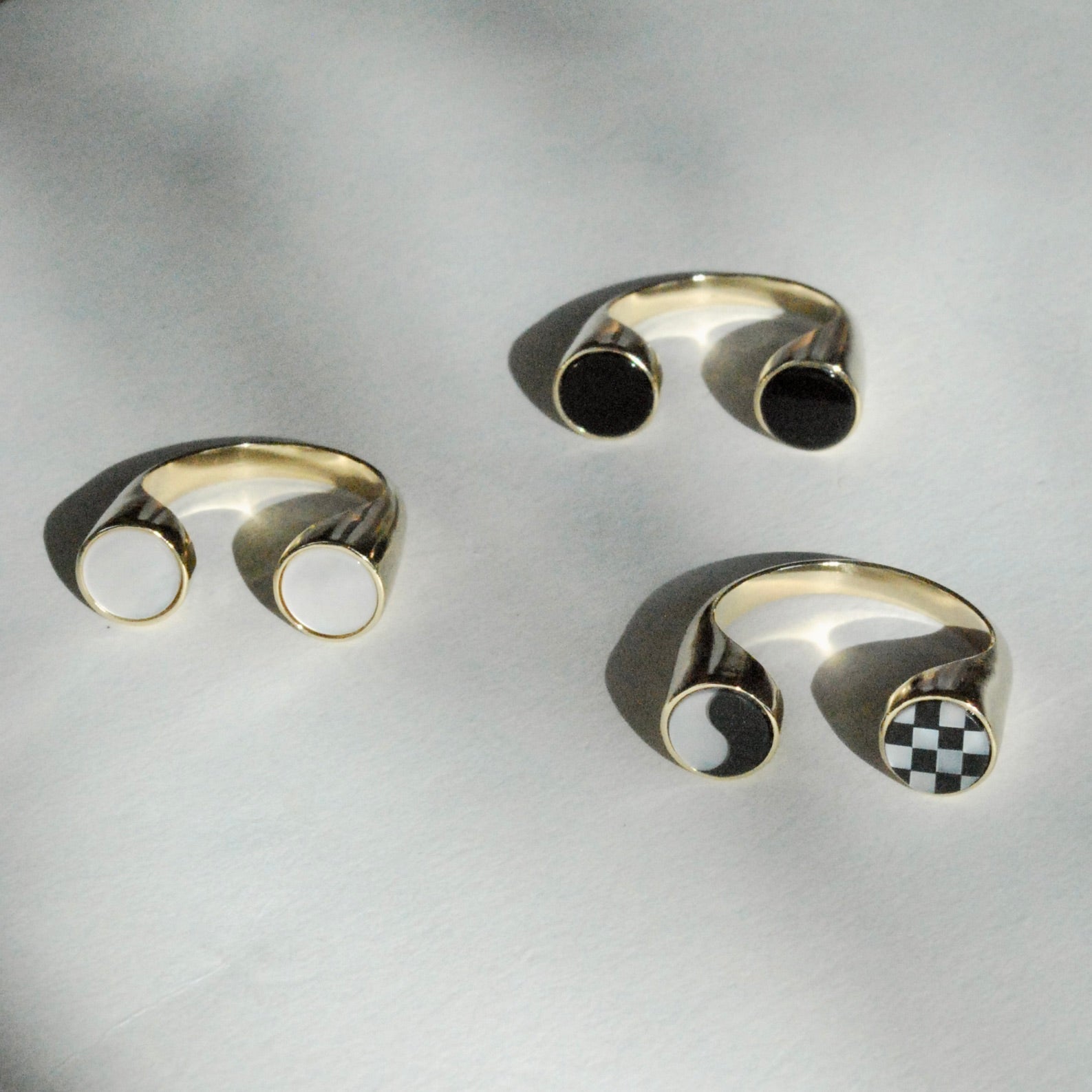 Three bronze rings with black and white stones displayed on a white background