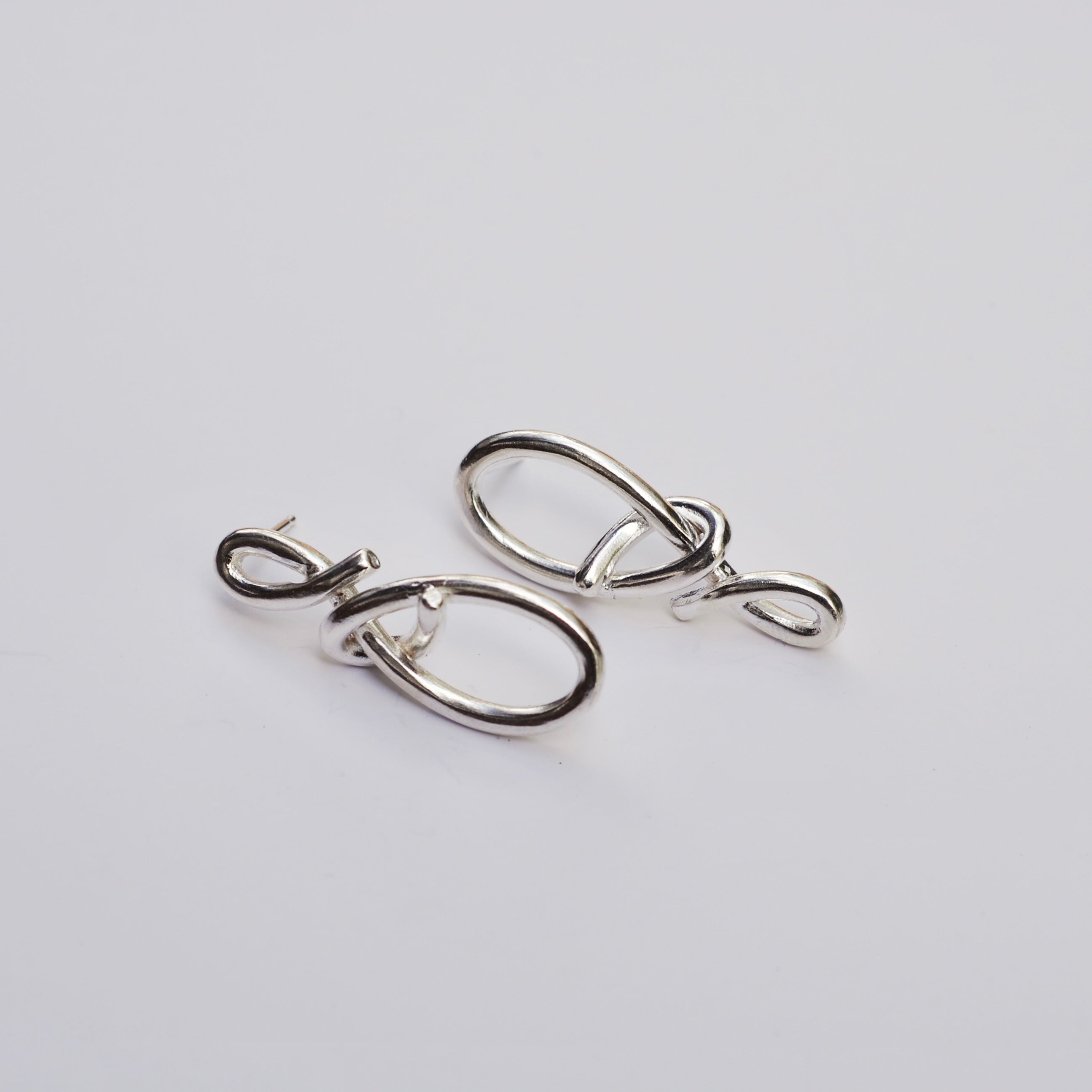 Silver knot earrings on a grey background