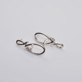 Silver knot earrings on a grey background