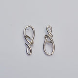 Silver asymmetrical knot post earrings on a grey background