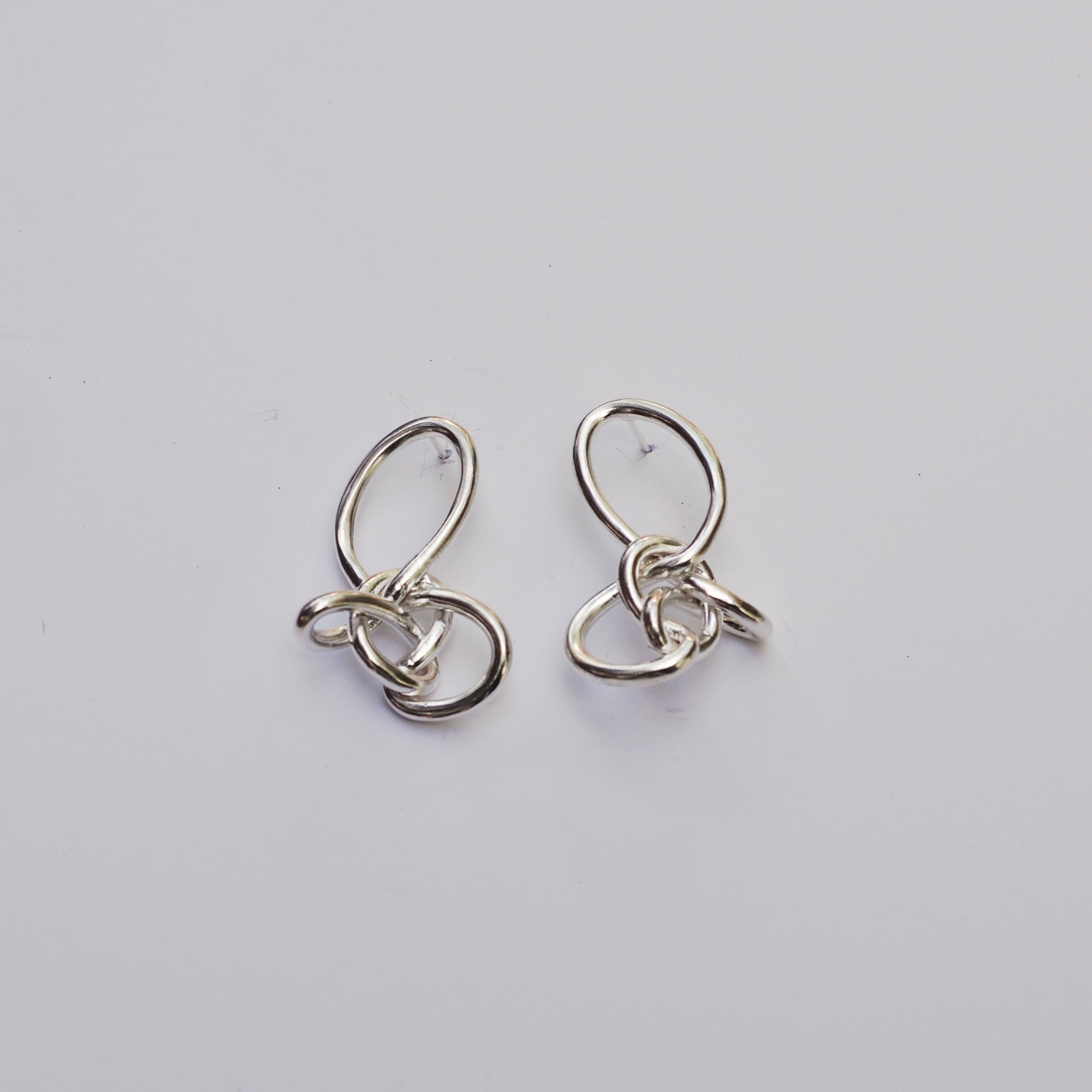 Silver knotted earrings on a light grey background