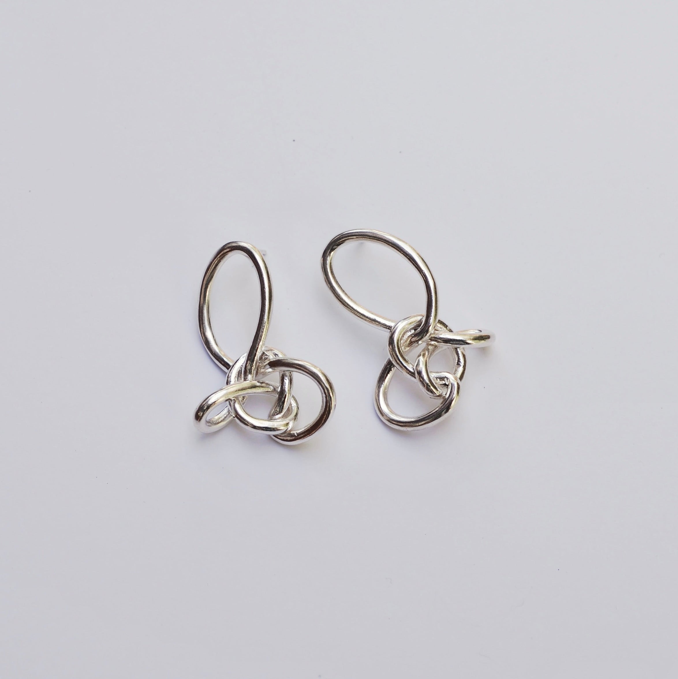 Silver knotted earrings on a grey background