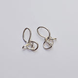 Silver knotted earrings on a grey background