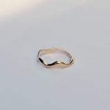 Gold ring with a wavy design on a light gray background