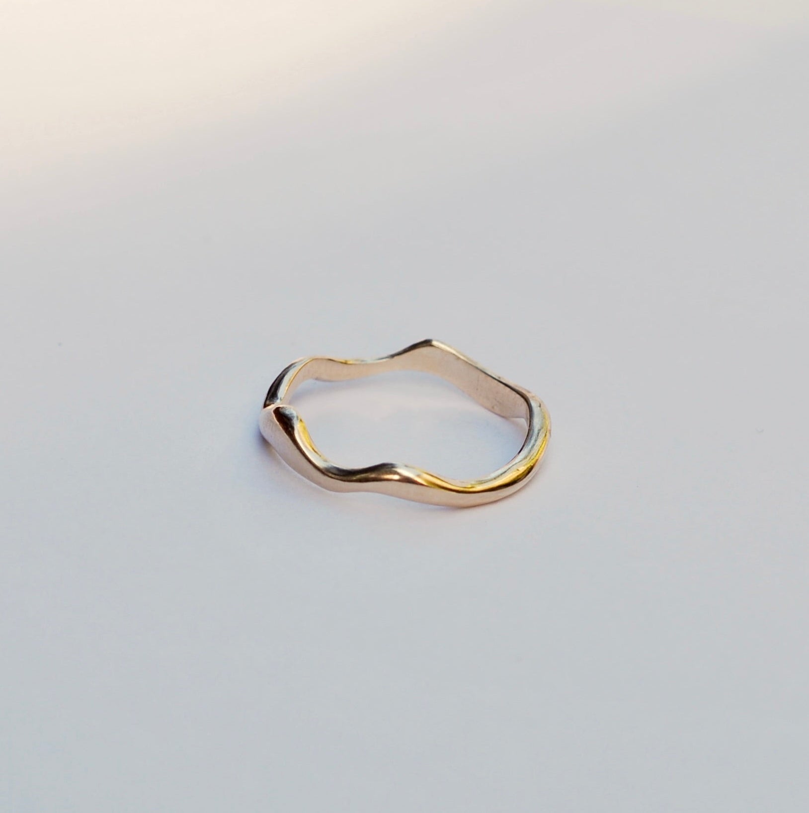 Gold squiggly ring on a light gray background