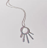 Silver necklace with a unique sunrise shaped pendant on a light gray background