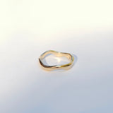 Gold organic wavy ring on a light gray background