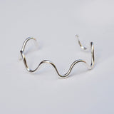 Silver wavy bracelet on a light gray background