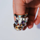 Stack of colorful rings on a finger against a light background