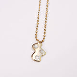 Gold necklace with a unique cloud shaped pendant with white mother of pearl stones on a light gray background