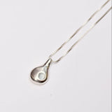 Silver teardrop pendant necklace with blue aquamarine stone on a white background