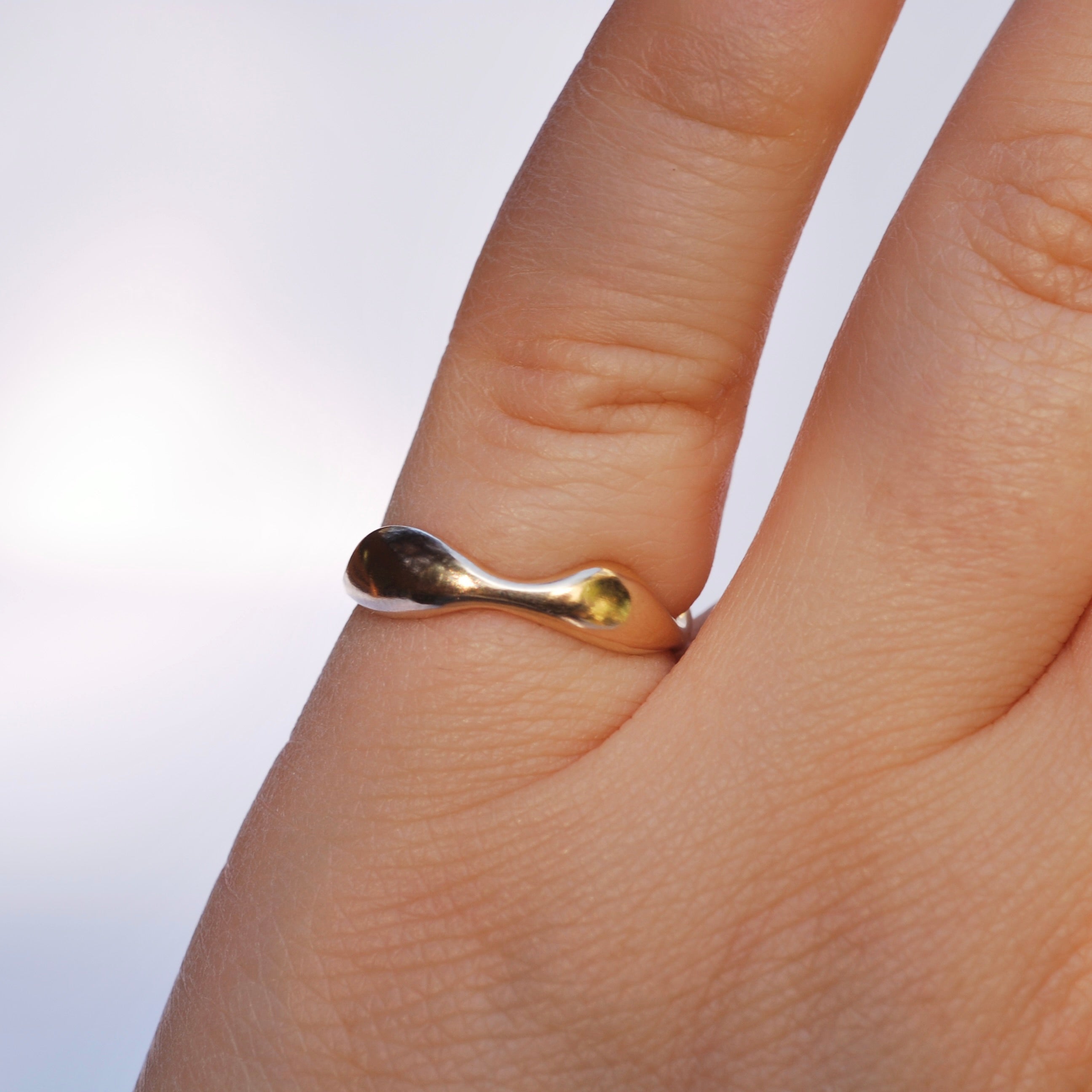 Gold ring on a finger with a plain background
