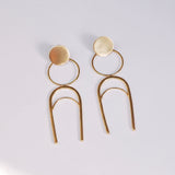 Gold colored geometric statement earrings on a white background