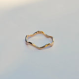 Gold wavy ring on a light gray background