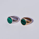 Two round signets with large green malachite inlay faces, one bronze and one silver on a white background