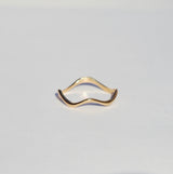 Thin wavy gold ring on a grey background