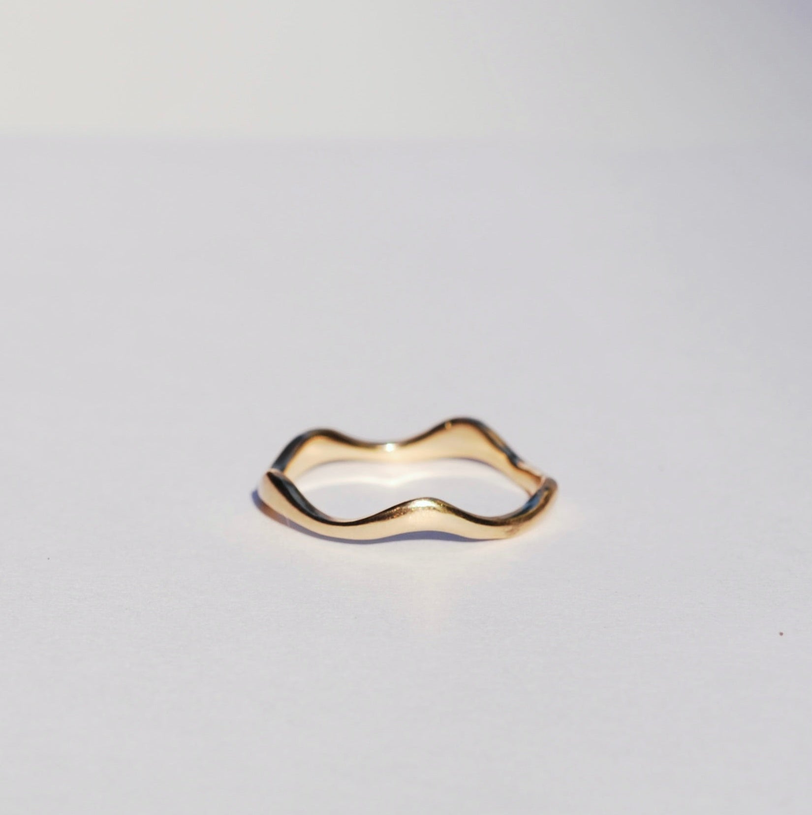Gold ring with a unique design on a light gray background