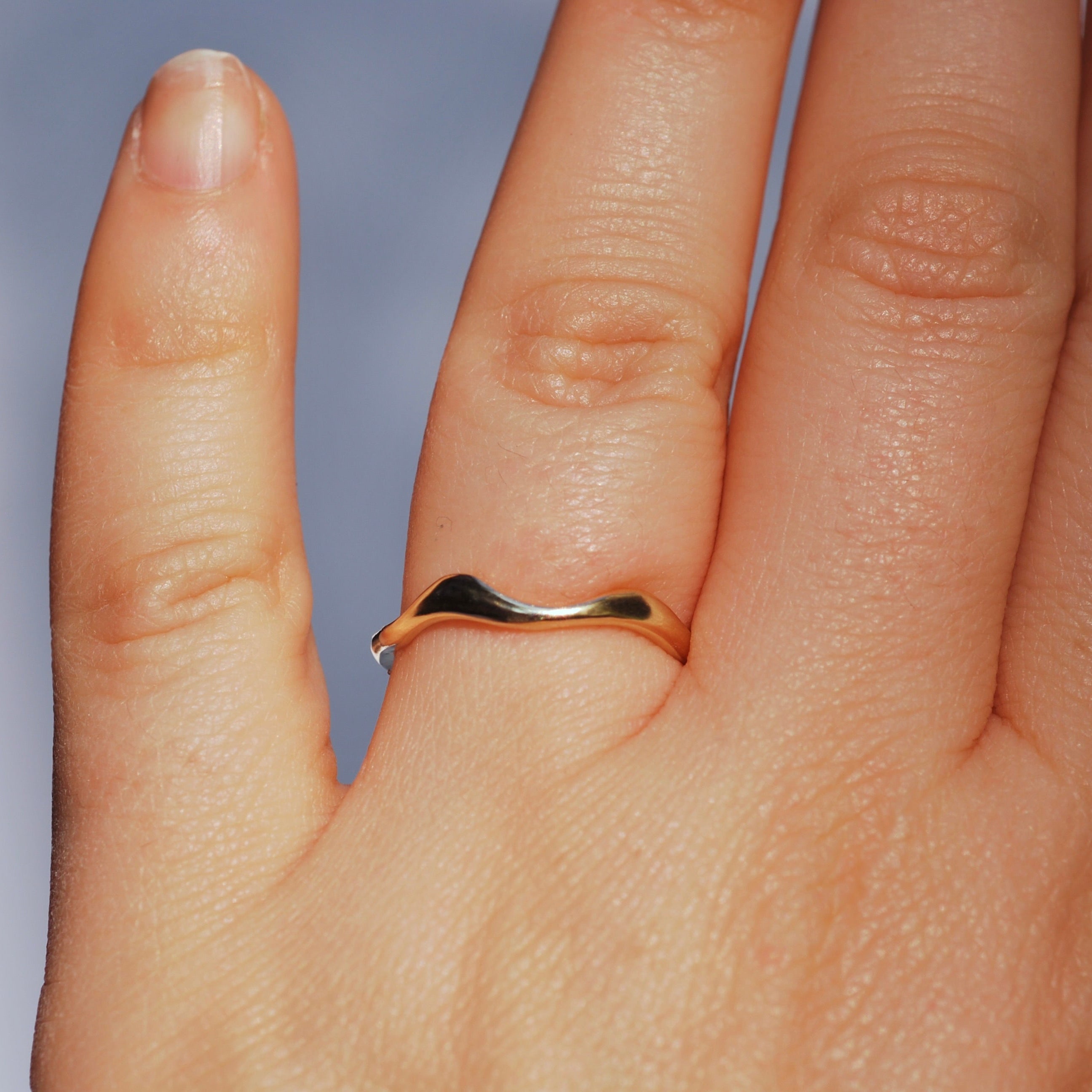 Close-up of a hand wearing a gold ring with a blurred background