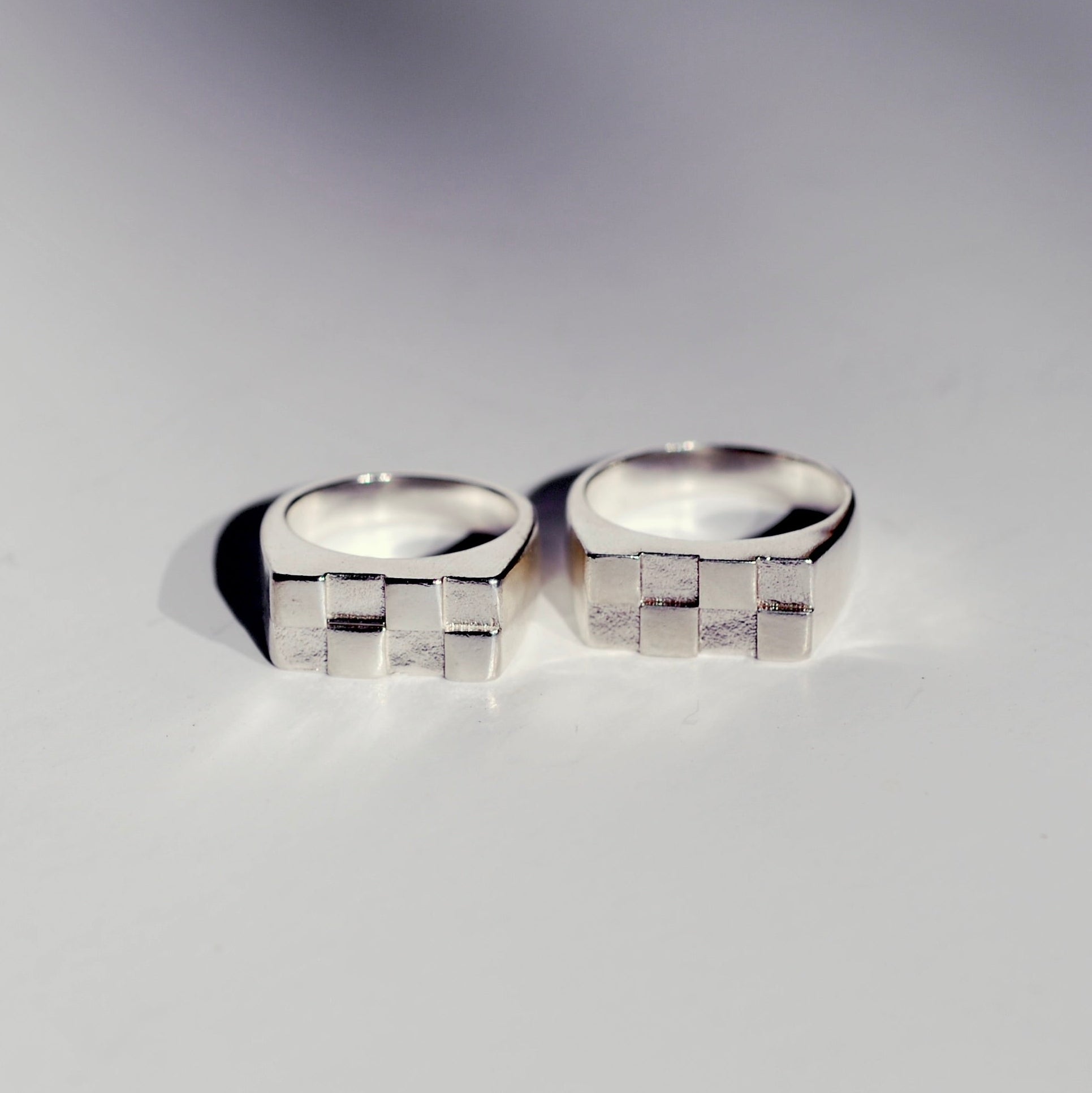 Two silver signet rings with a rectangle shape and checkerboard pattern