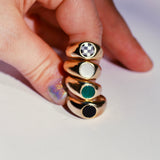 Finger holding a stack of four bubble inlay rings in bronze with different color stones