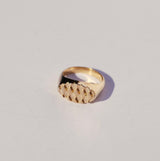 Bronze oval signet ring with a diamond textured design on a light gray background