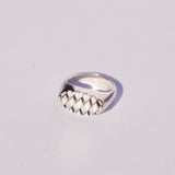 Silver oval signet  ring with a diamond textured face on a light gray background