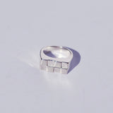 Silver rectangle signet ring with a checkerboard geometric design on a light gray background