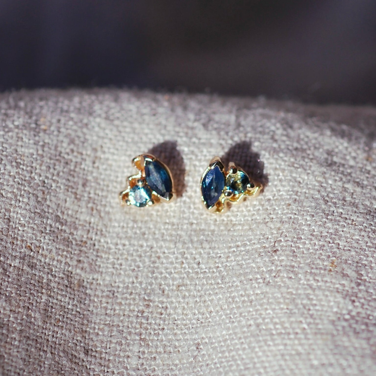 Pair of earrings with blue stones on a textured fabric surface